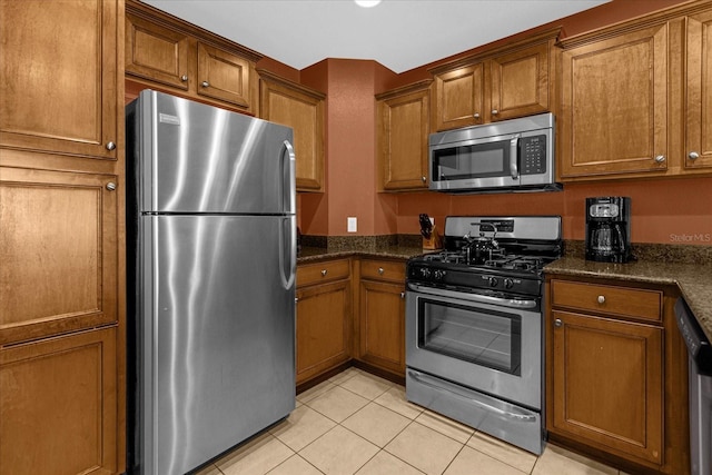 kitchen featuring light tile patterned floors, stainless steel appliances, and dark stone counters