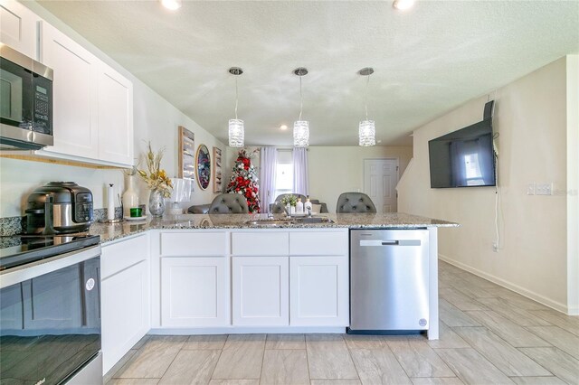 kitchen featuring white cabinets, stainless steel appliances, hanging light fixtures, and sink