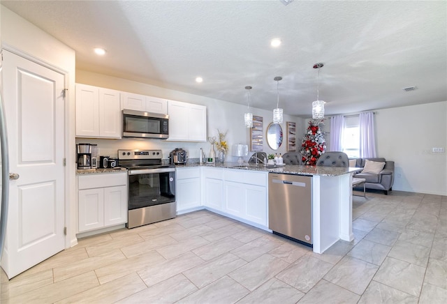 kitchen featuring kitchen peninsula, pendant lighting, stainless steel appliances, and white cabinets