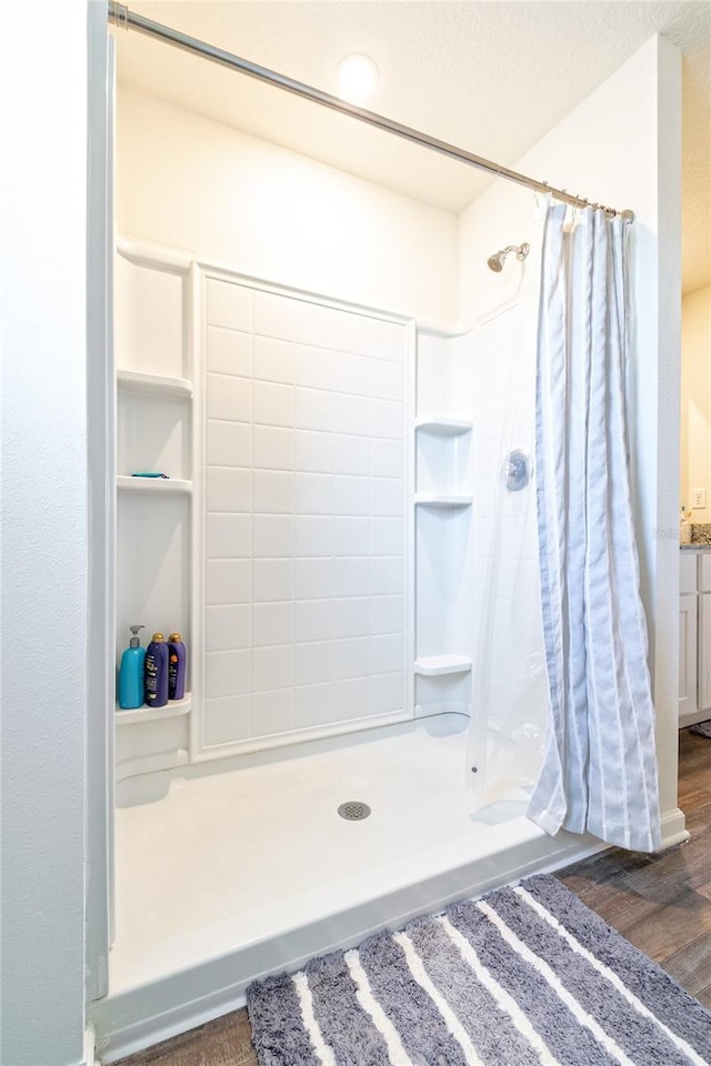 bathroom with curtained shower, vanity, wood-type flooring, and a textured ceiling