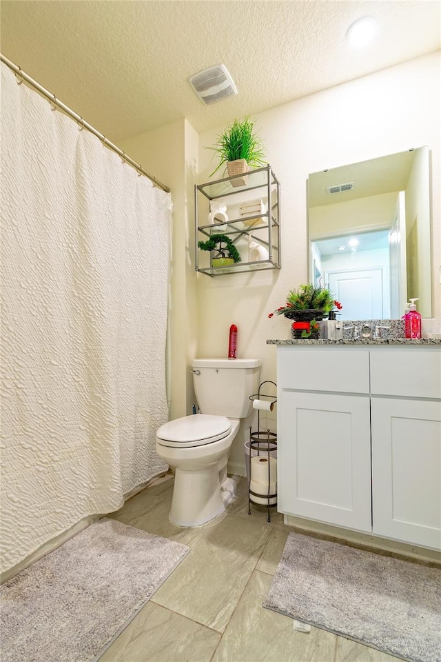 bathroom featuring vanity, toilet, and a textured ceiling