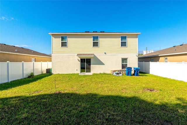 back of house with central AC unit and a lawn