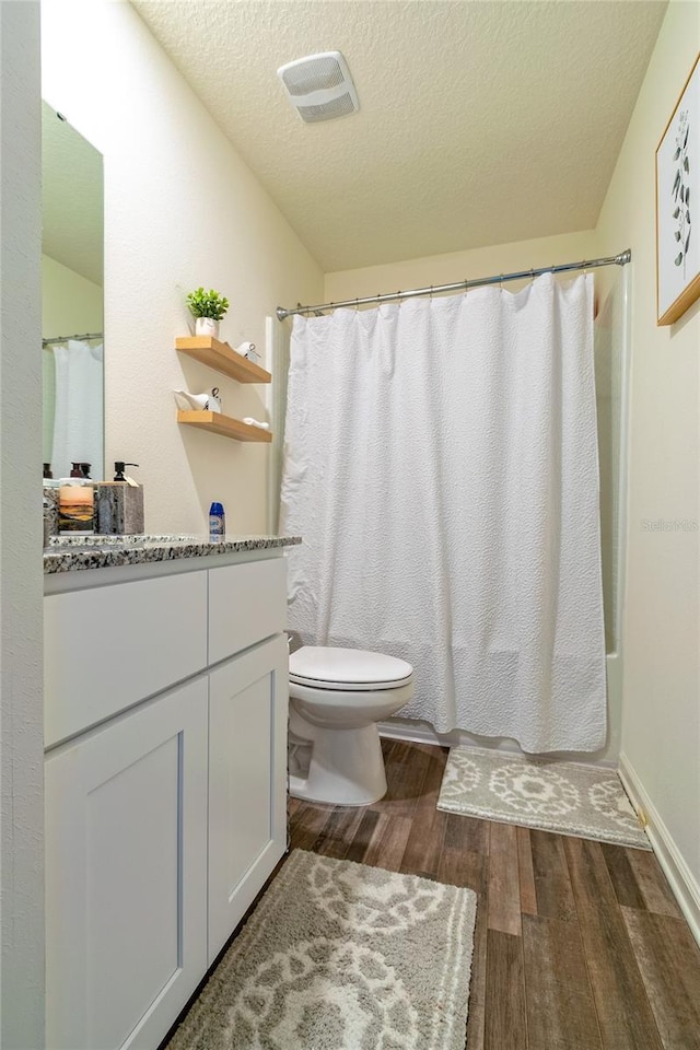 full bathroom with vanity, a textured ceiling, wood-type flooring, shower / bathtub combination with curtain, and toilet