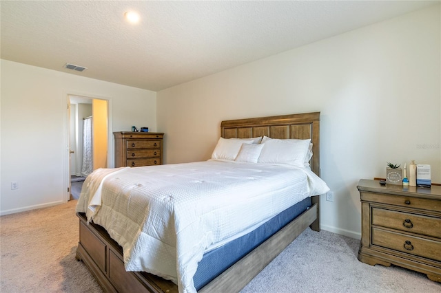 carpeted bedroom with a textured ceiling and ensuite bath