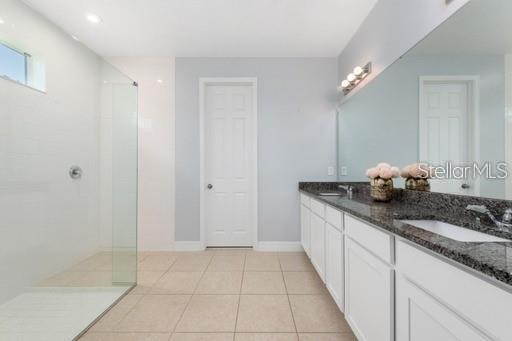 bathroom with a shower, tile patterned flooring, and vanity