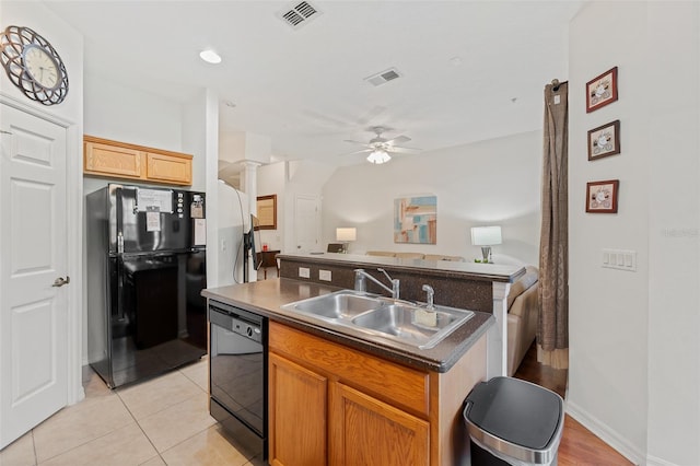 kitchen featuring ornate columns, ceiling fan, sink, black appliances, and a center island with sink