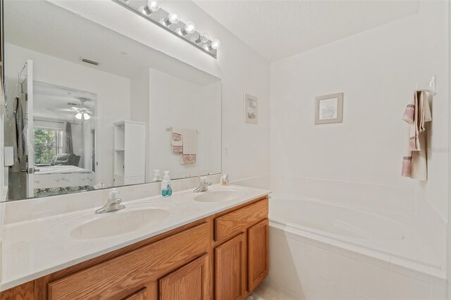 bathroom with vanity, ceiling fan, and tiled tub