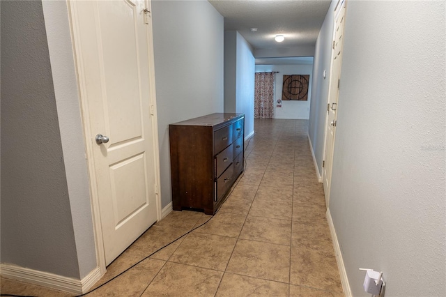 hallway with light tile patterned floors and a textured ceiling