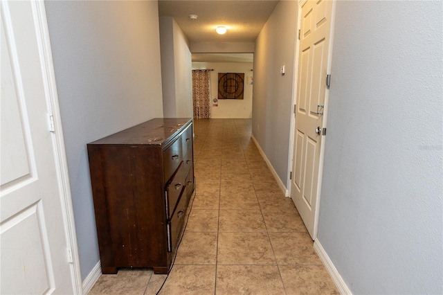 hallway with light tile patterned floors and a textured ceiling