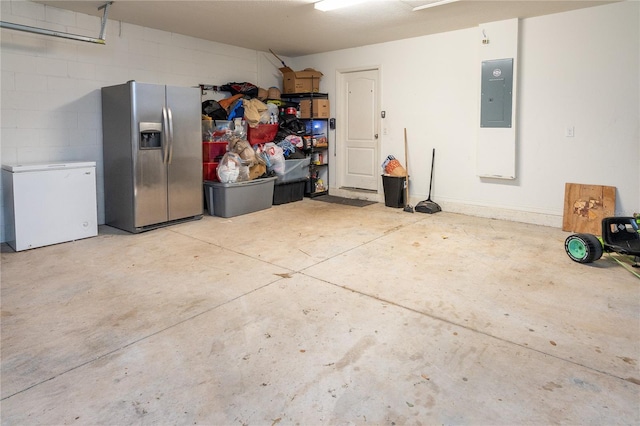 garage with electric panel, stainless steel refrigerator with ice dispenser, and white refrigerator