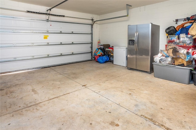 garage with stainless steel fridge with ice dispenser and white refrigerator