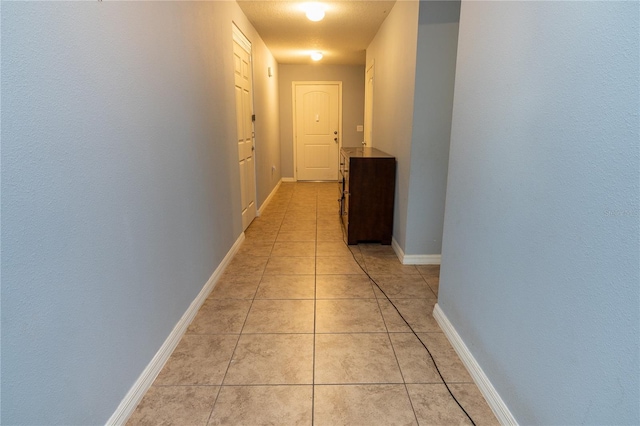 hall featuring light tile patterned floors and a textured ceiling