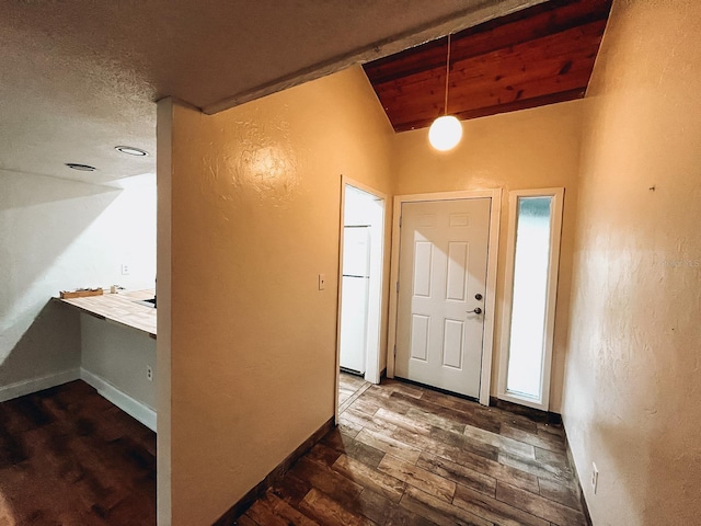 foyer with dark wood-type flooring and vaulted ceiling