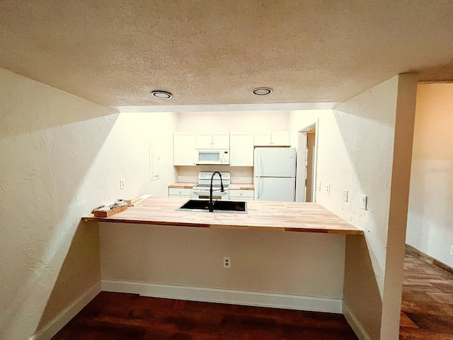 kitchen featuring white appliances, white cabinets, sink, hardwood / wood-style flooring, and kitchen peninsula