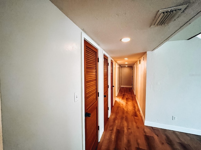 corridor with a textured ceiling and dark hardwood / wood-style floors