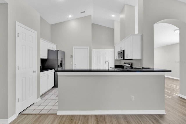 kitchen with white cabinetry, stainless steel appliances, high vaulted ceiling, and light hardwood / wood-style flooring