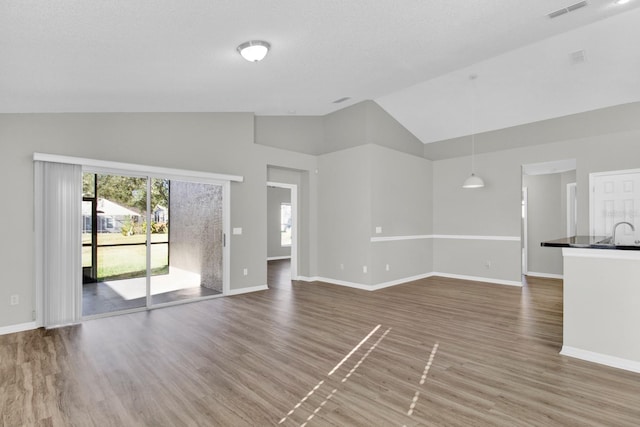 unfurnished living room with hardwood / wood-style floors, sink, and high vaulted ceiling