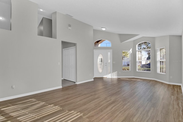 foyer entrance with a textured ceiling, wood-type flooring, and a high ceiling