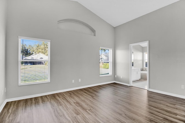 empty room with hardwood / wood-style flooring and high vaulted ceiling