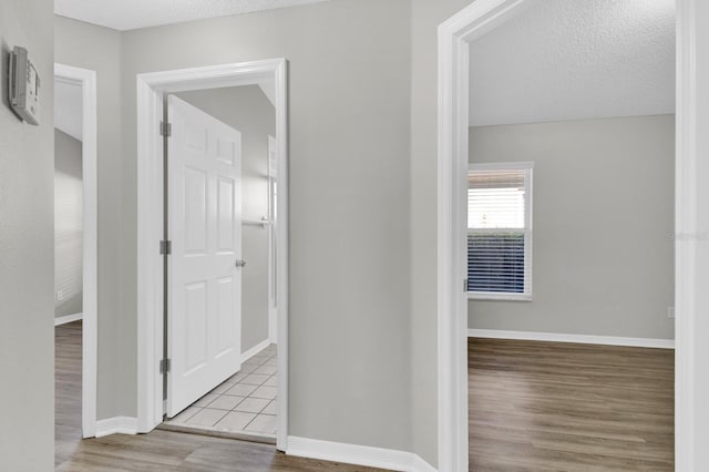 hallway with a textured ceiling and light wood-type flooring