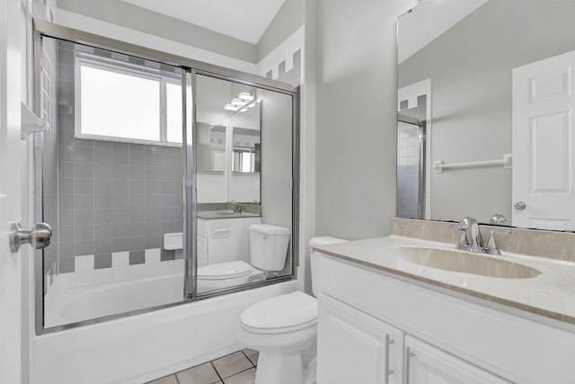 full bathroom with vanity, shower / bath combination with glass door, vaulted ceiling, tile patterned flooring, and toilet