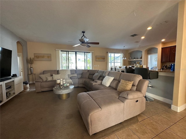 living room featuring ceiling fan, light tile patterned floors, and a textured ceiling