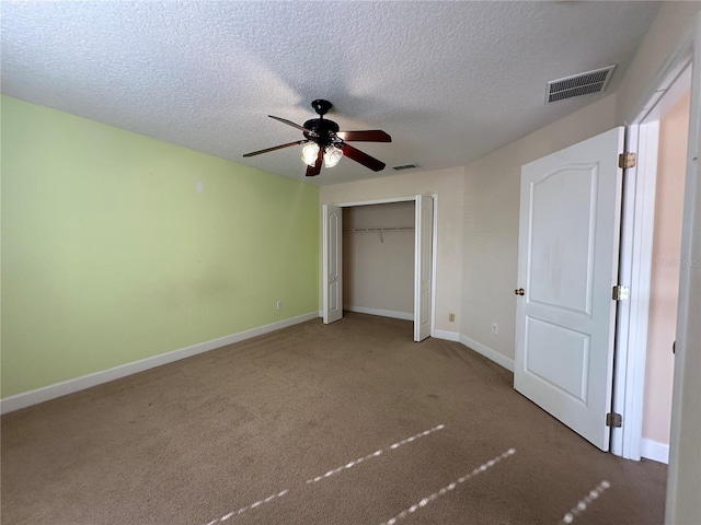 unfurnished bedroom with carpet flooring, ceiling fan, a textured ceiling, and a closet