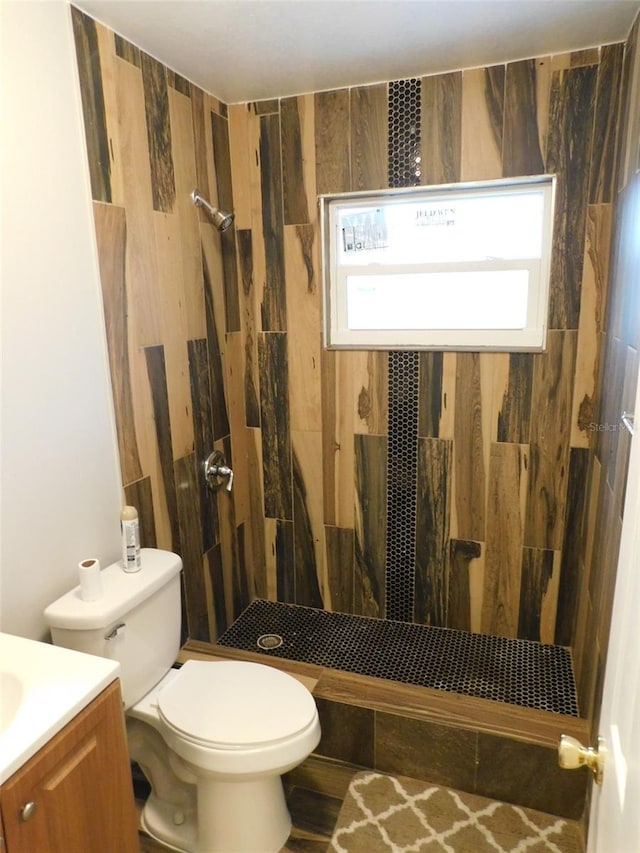 bathroom featuring tiled shower, vanity, and toilet