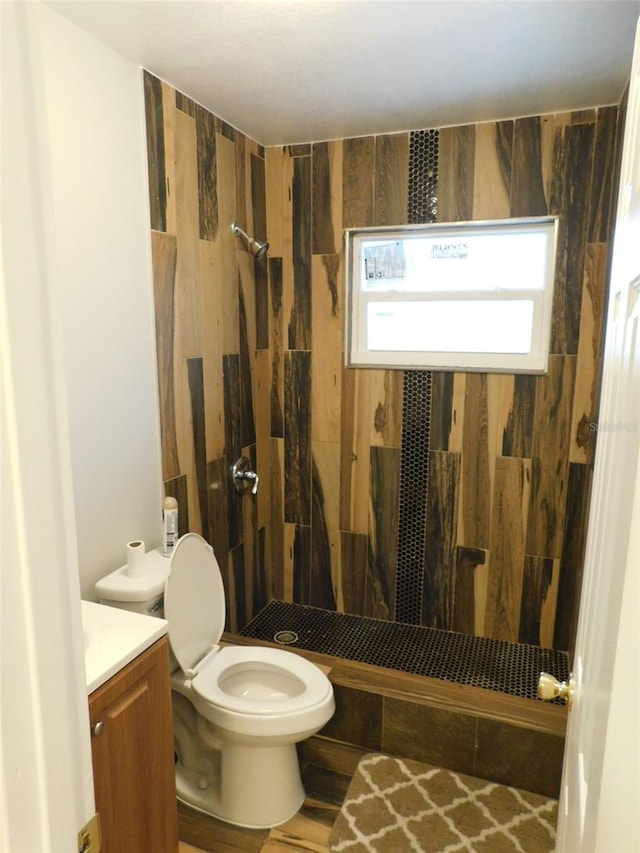 bathroom featuring vanity, toilet, and a tile shower