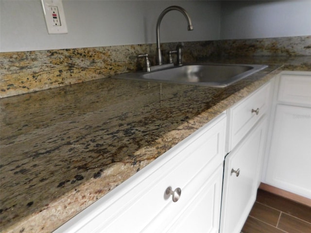 kitchen featuring dark hardwood / wood-style floors, white cabinetry, dark stone counters, and sink