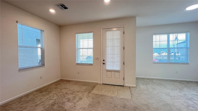 doorway with a wealth of natural light and light carpet