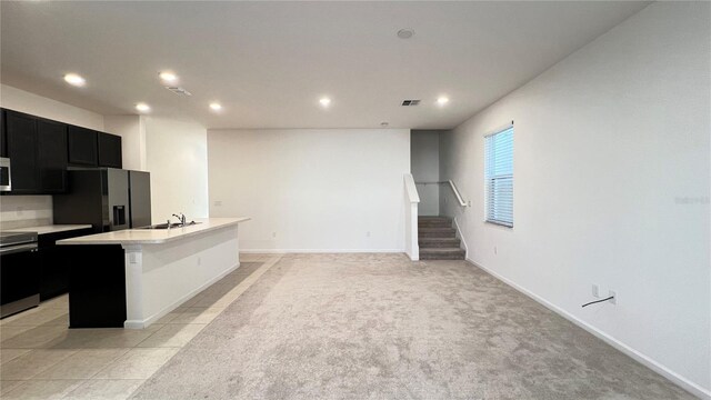 kitchen featuring a center island with sink, stainless steel appliances, a breakfast bar area, and light carpet