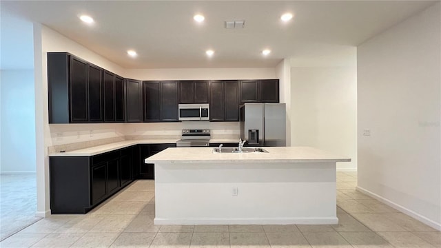 kitchen featuring light tile patterned flooring, sink, an island with sink, and appliances with stainless steel finishes