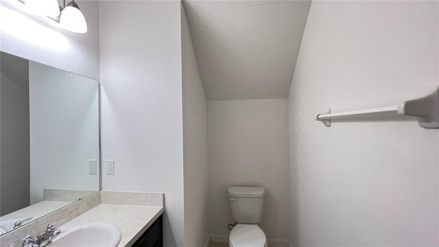 bathroom featuring a textured ceiling, vanity, vaulted ceiling, and toilet