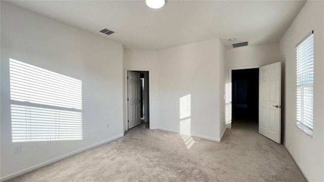 unfurnished bedroom with light colored carpet and multiple windows