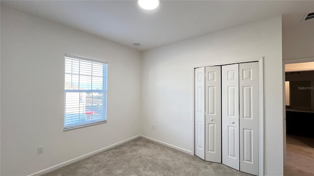 unfurnished bedroom with a closet and light colored carpet