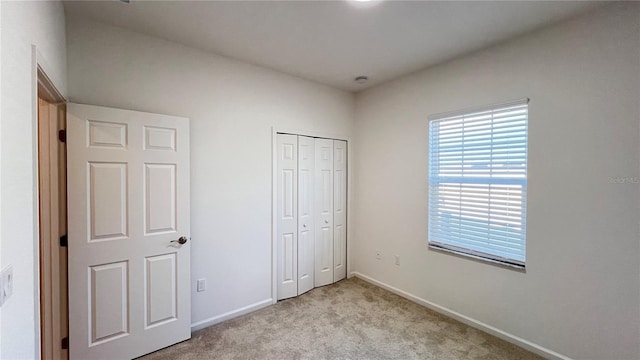 unfurnished bedroom with light colored carpet and a closet