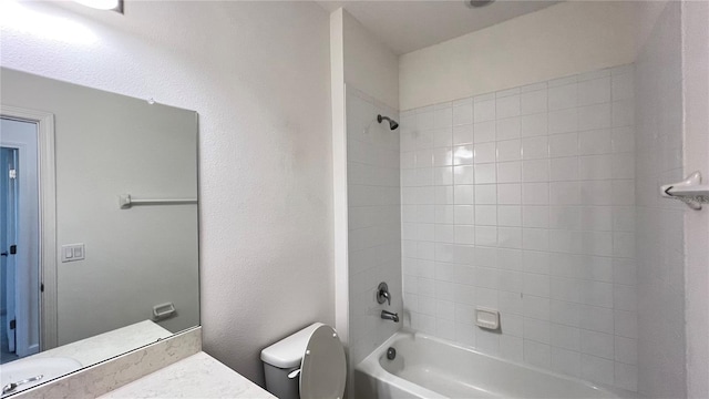 full bathroom with tiled shower / bath, vanity, and toilet