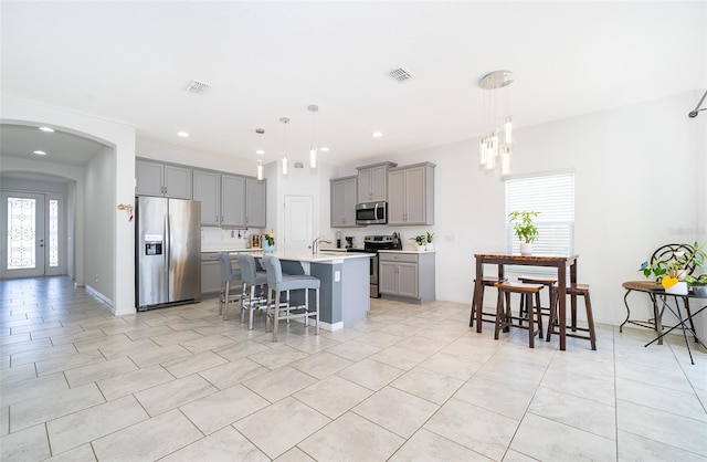 kitchen with a healthy amount of sunlight, a breakfast bar, an island with sink, and stainless steel appliances