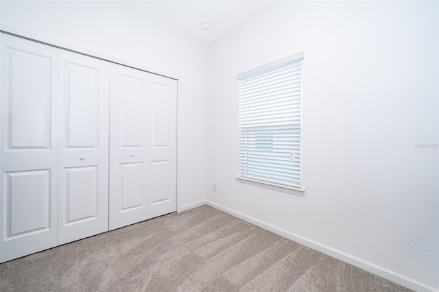 unfurnished bedroom featuring light carpet and a closet