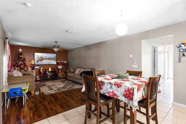 dining room with ceiling fan, light hardwood / wood-style flooring, and a textured ceiling