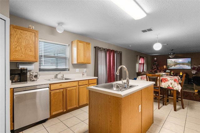 kitchen with a textured ceiling, stainless steel dishwasher, a kitchen island with sink, and sink