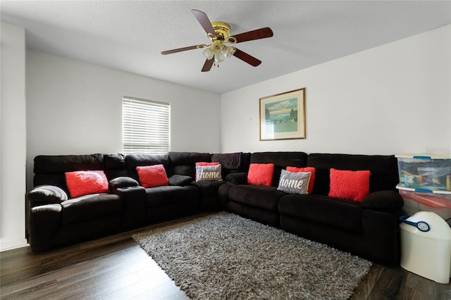 living room featuring dark hardwood / wood-style floors, ceiling fan, and a textured ceiling