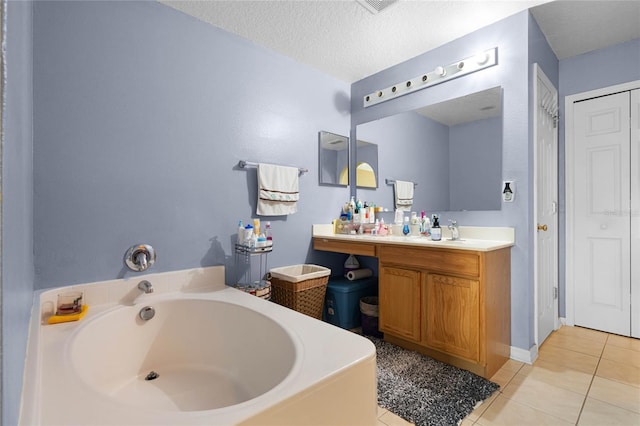 bathroom with tile patterned floors, a bathing tub, vanity, and a textured ceiling