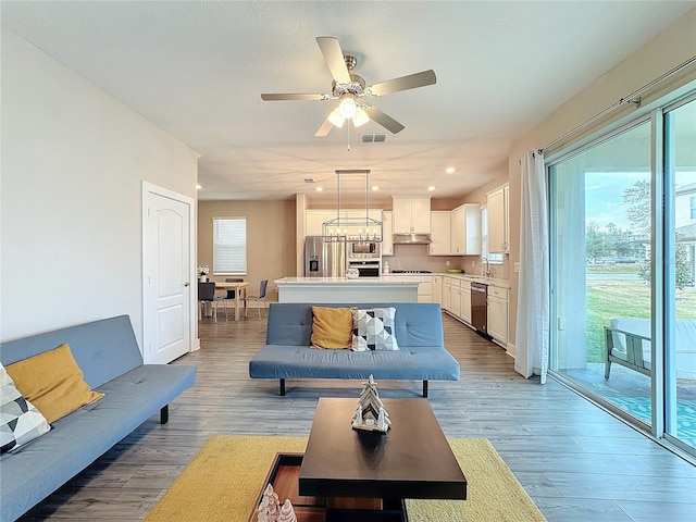 living room featuring ceiling fan, light hardwood / wood-style flooring, and a healthy amount of sunlight