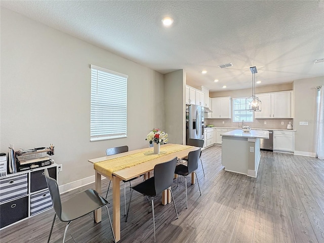 dining room featuring light hardwood / wood-style floors, sink, and a textured ceiling