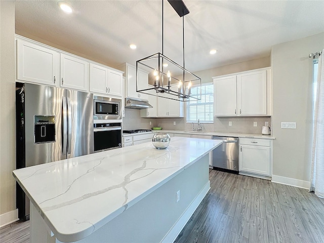 kitchen with a center island, white cabinets, hanging light fixtures, and appliances with stainless steel finishes