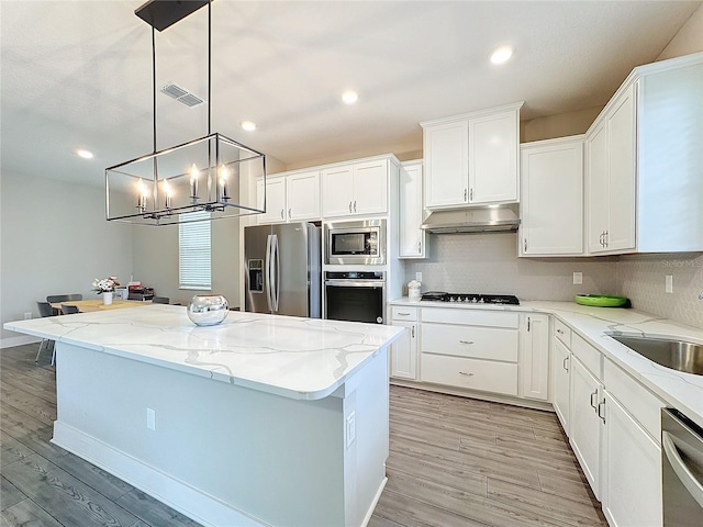 kitchen featuring pendant lighting, a center island, white cabinets, and stainless steel appliances