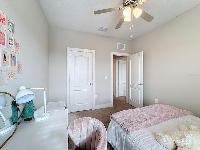 carpeted bedroom featuring ceiling fan and a textured ceiling