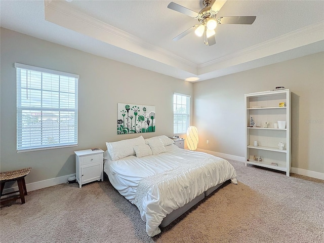 bedroom with a raised ceiling, ceiling fan, carpet flooring, and ornamental molding